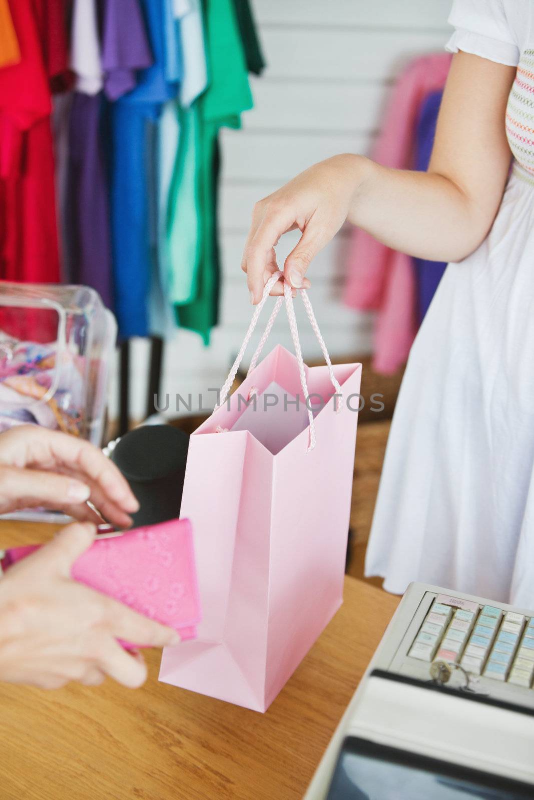 Caucasian saleswoman giving a shopping bag to a customer in a clothes store