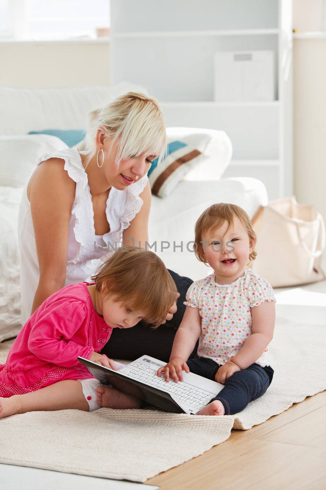 Laughing little girl using a laptop with her family  by Wavebreakmedia
