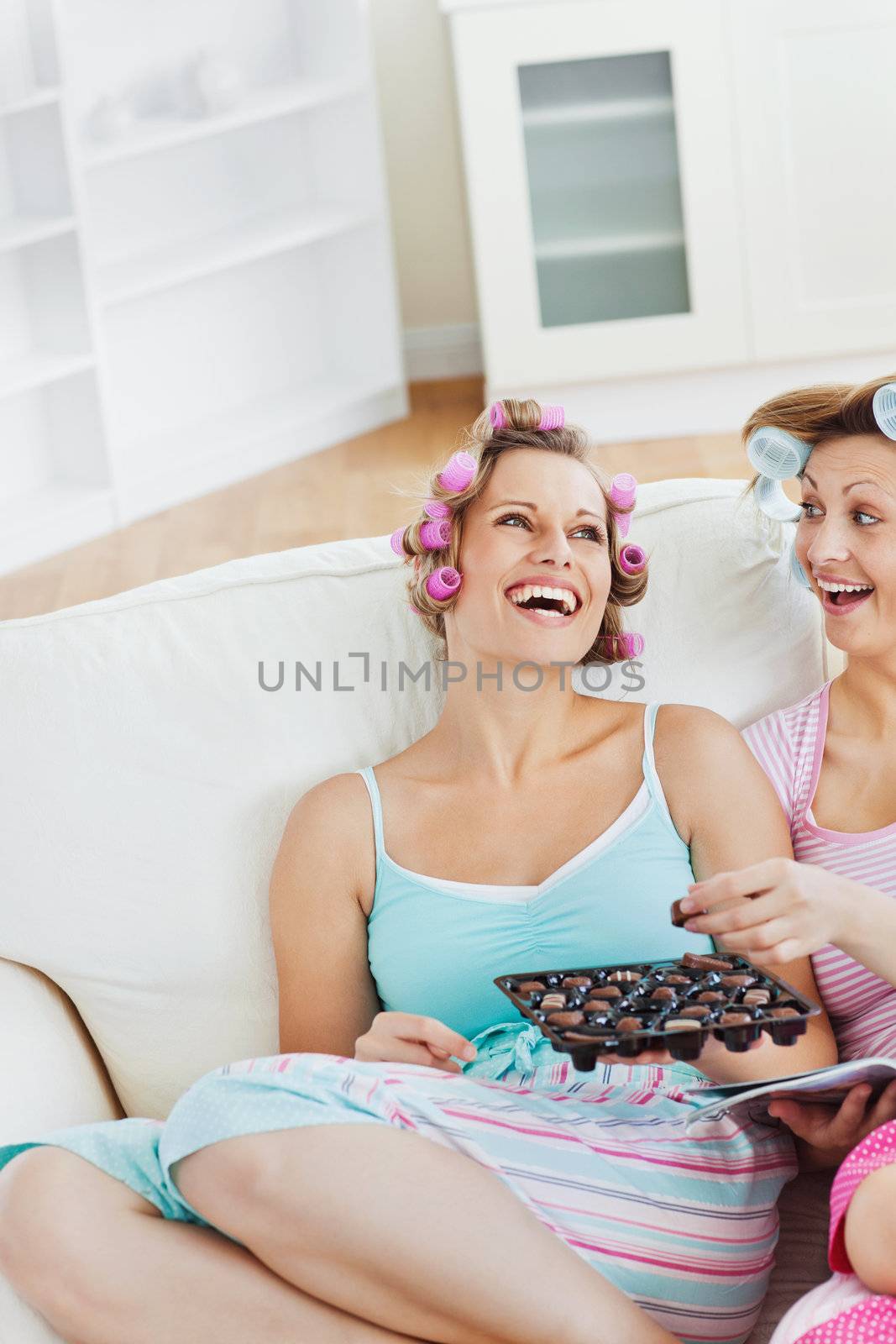 Laughing friends eating chocolate at home in the living-room