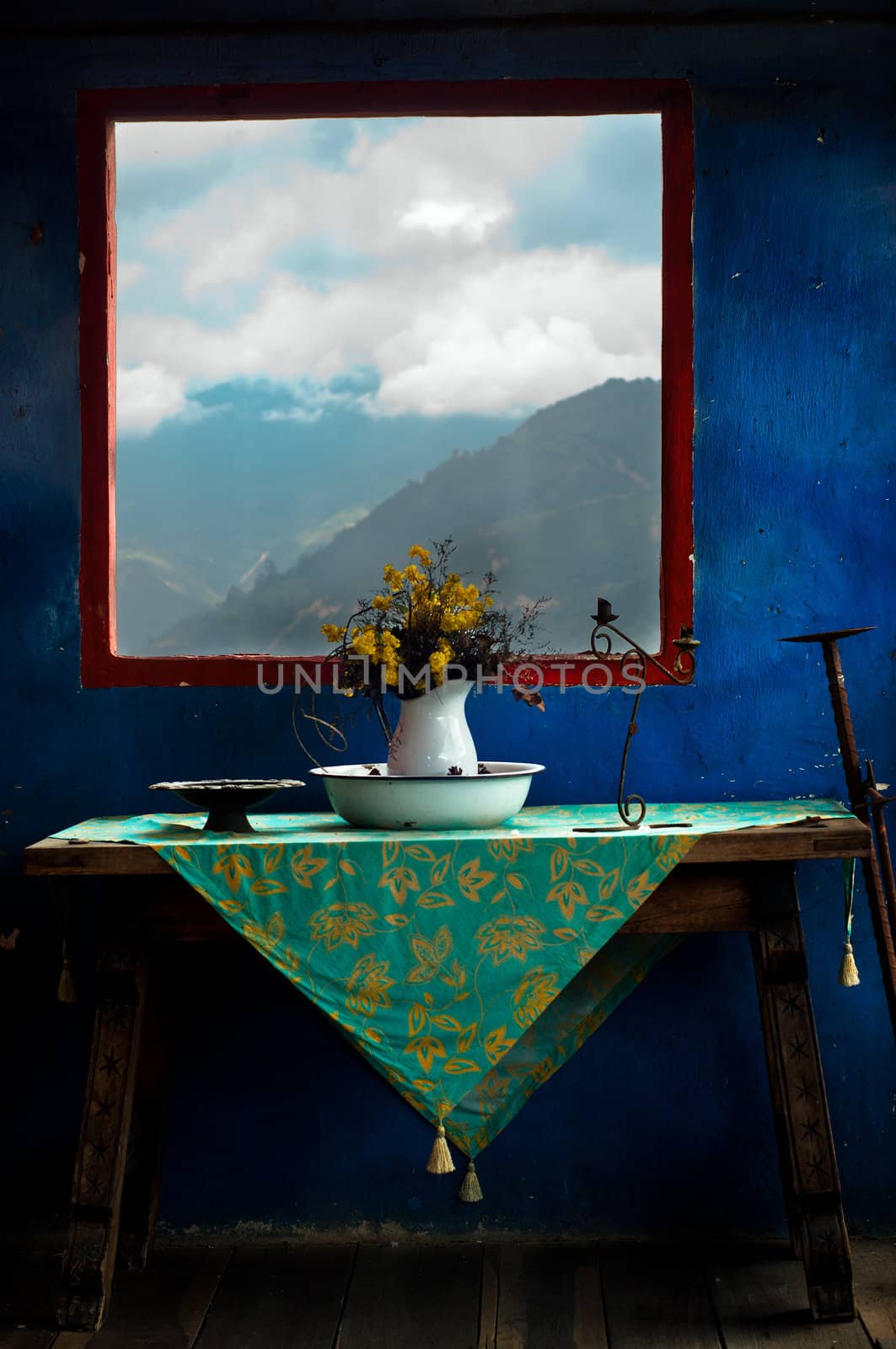 Flowers sitting on a table with a blue wall and a mountain behind them.