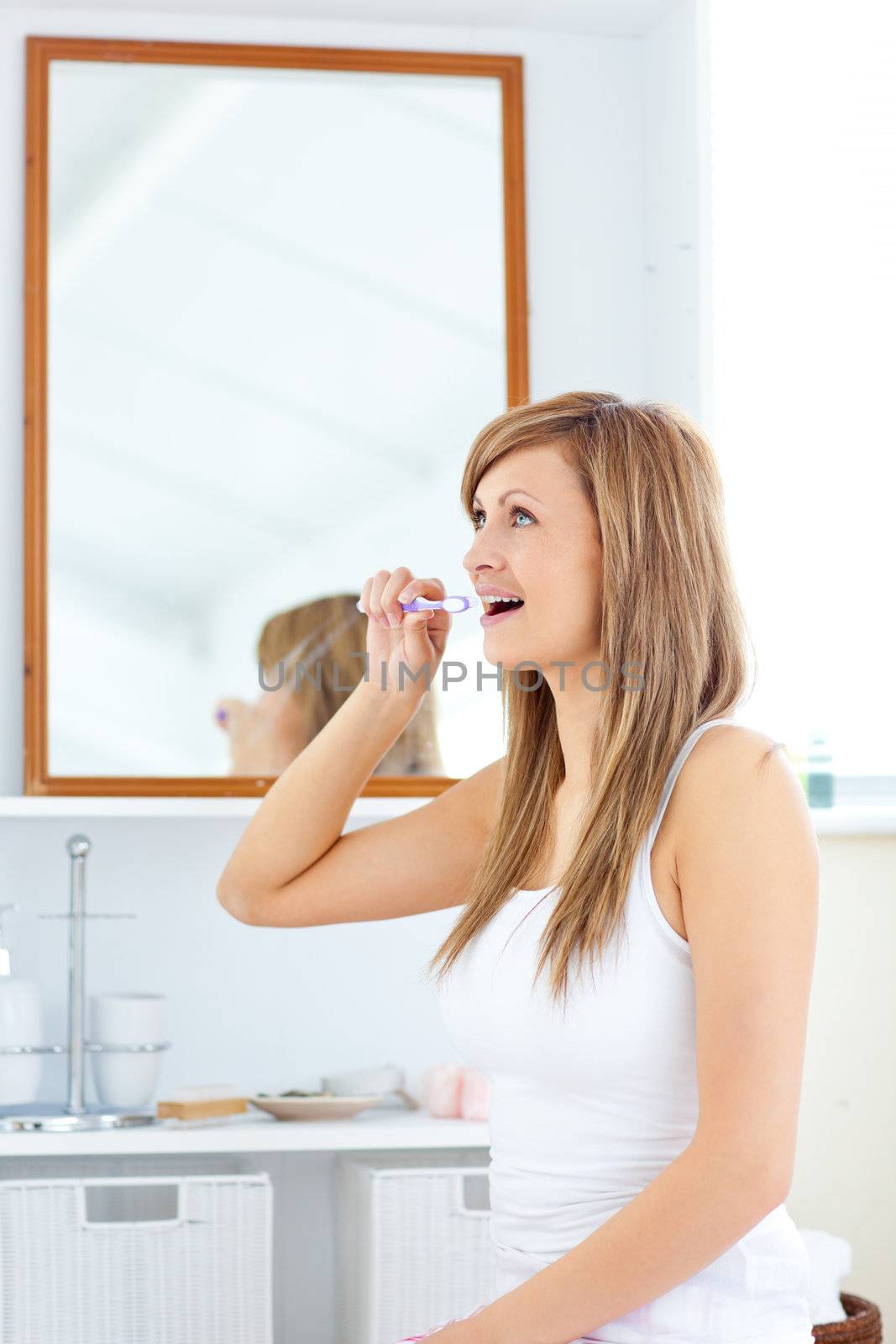 Blond young woman brushing her teeth in the bathroom at home