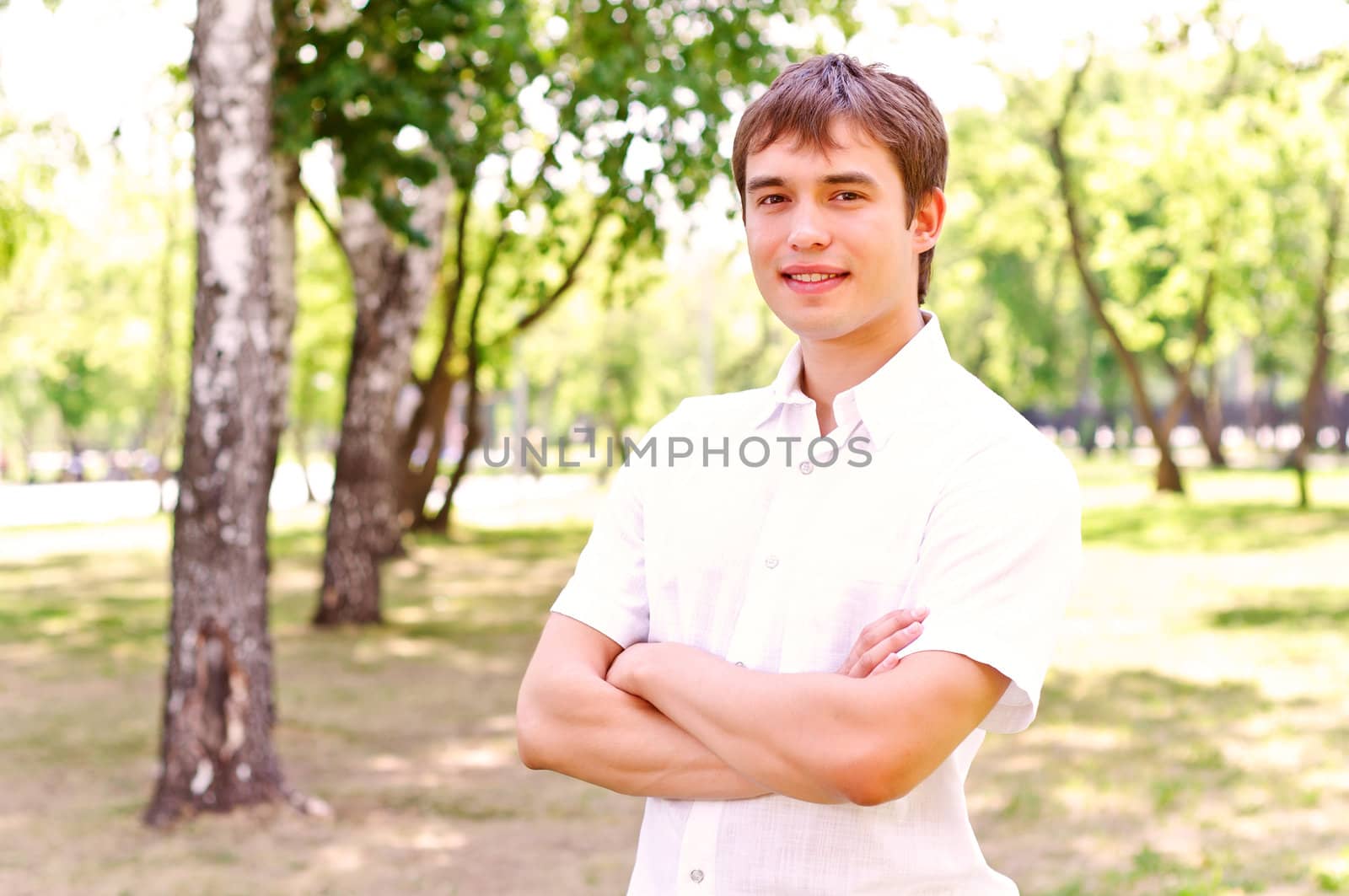 Portrait of man outside in park, crossed his arms