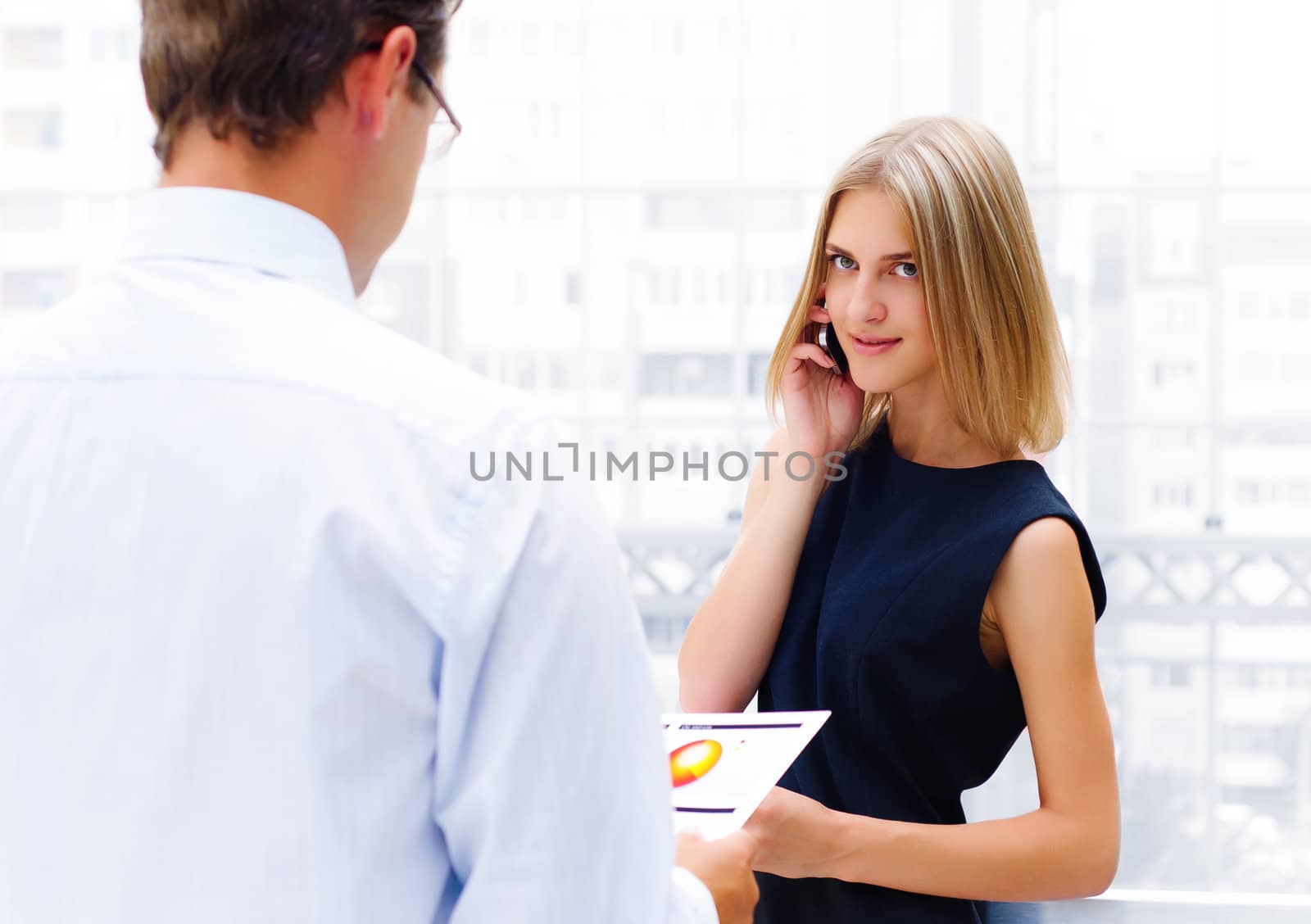 business male and business female discuss reports, Woman talking on cell phone