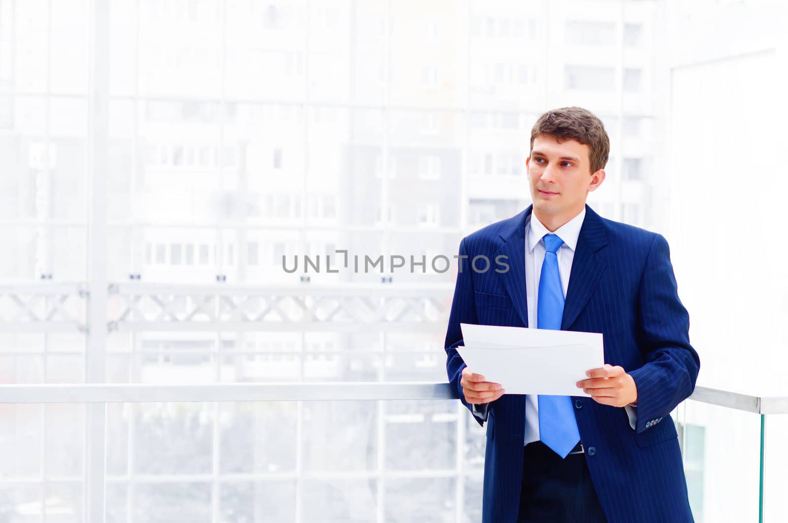 Smiling business man on the balcony, holdings reports