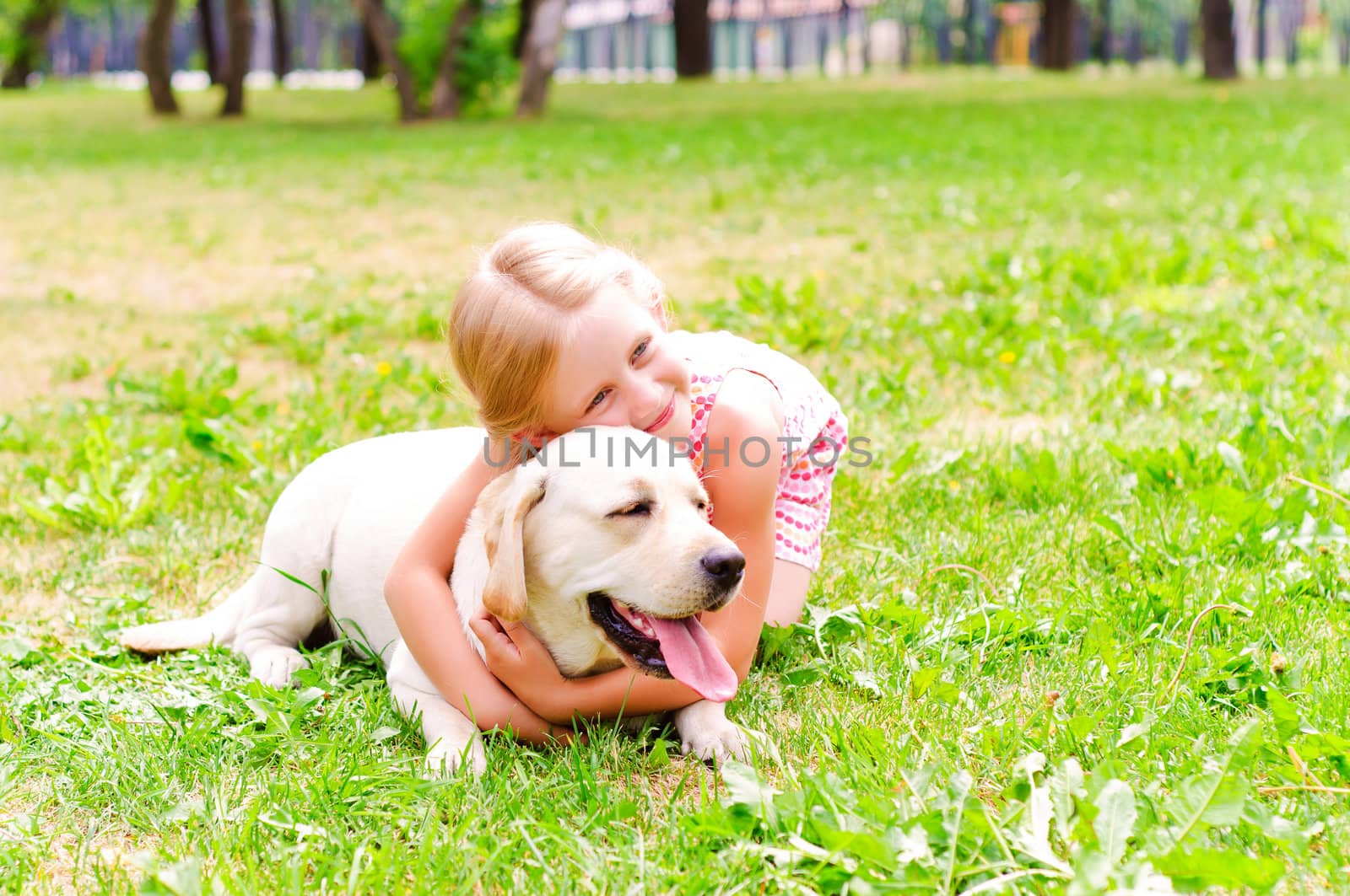 girl and she lablador, hugging in the park lying on the grass