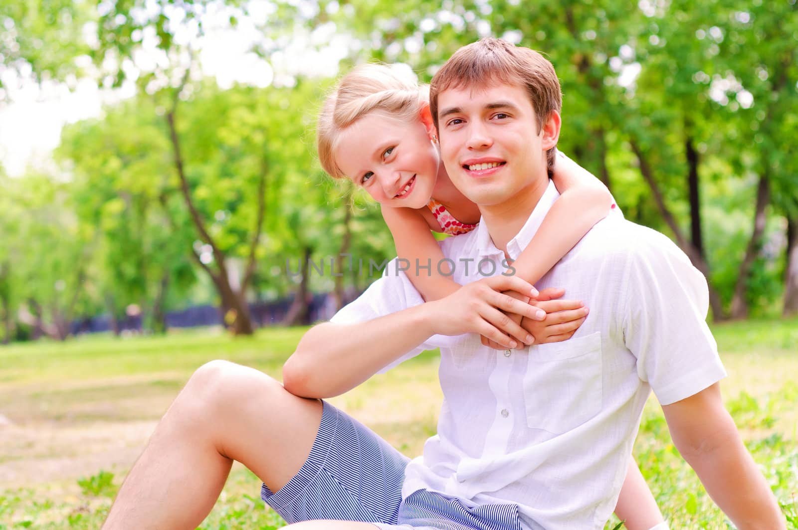 Father and daughter sitting together on the grass, and spend time with family