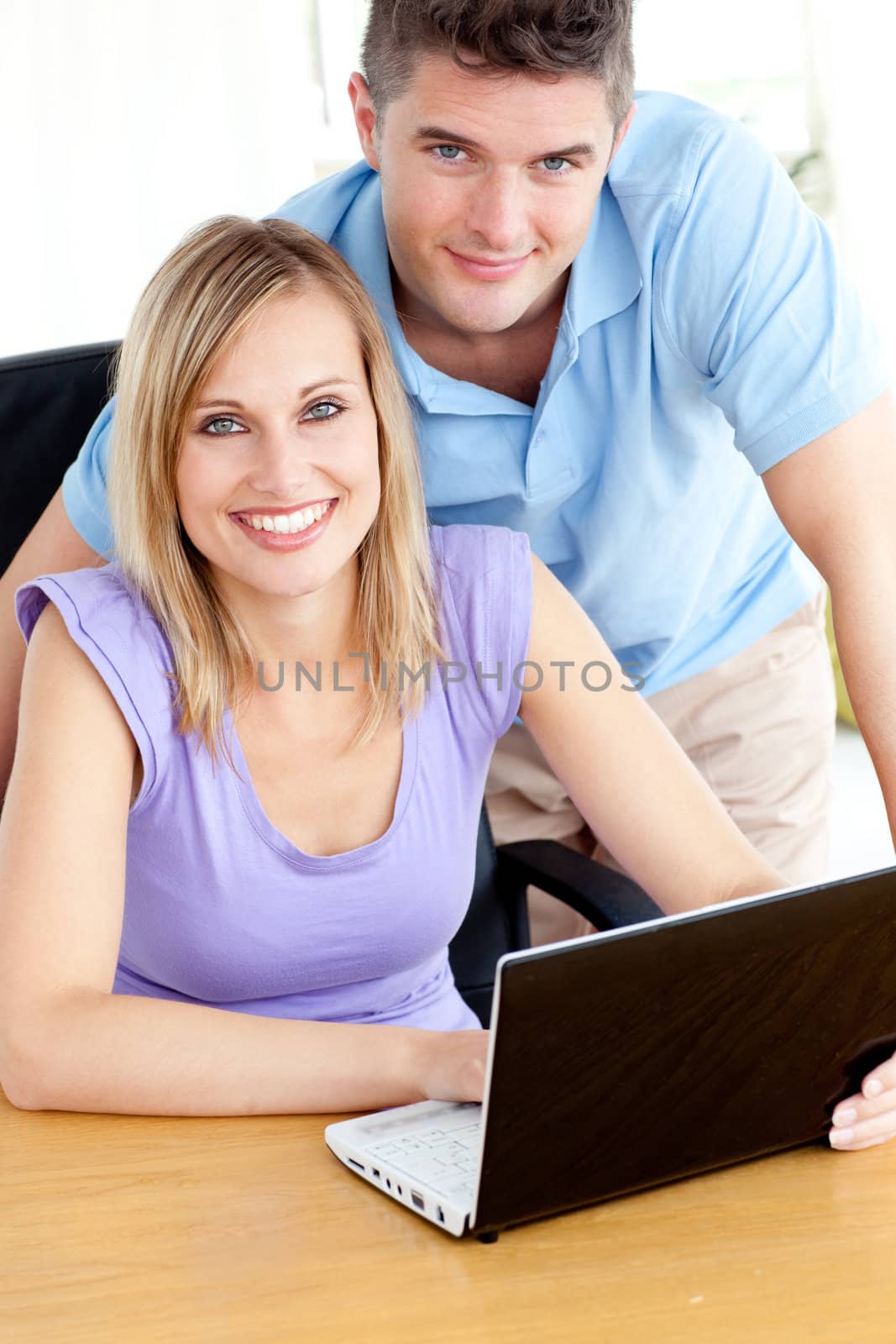 Joyful couple using a laptop sitting in the kitchen by Wavebreakmedia