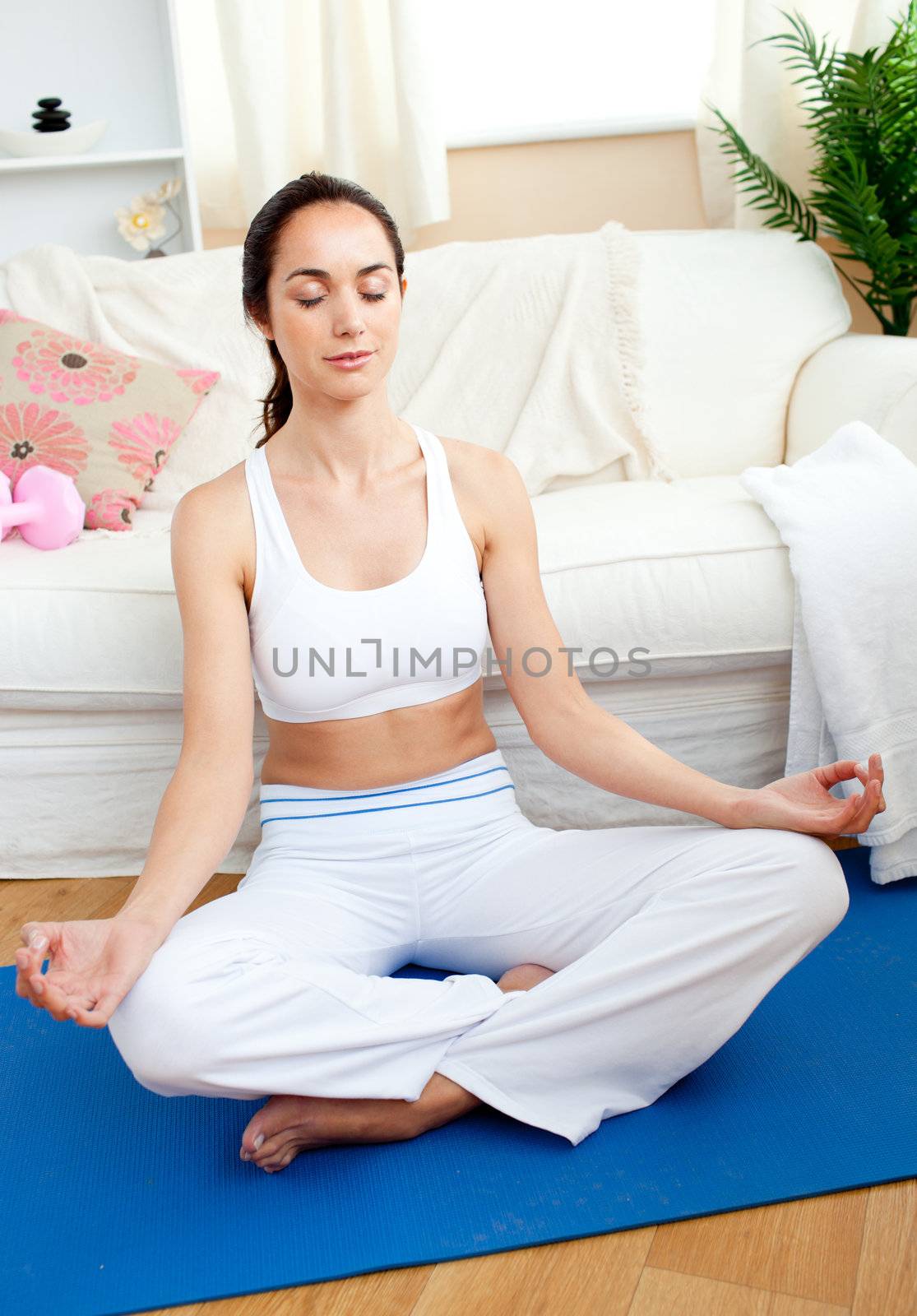 Relaxed woman doing yoga sitting in her living-room at home