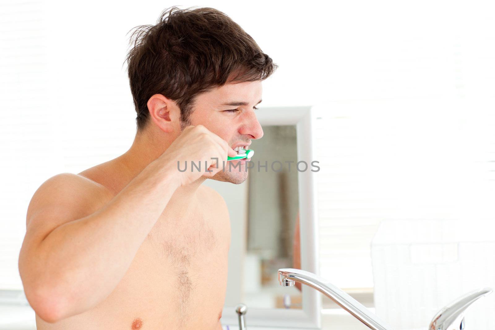 Handsome young man brushing his teeth in the bathroom at home