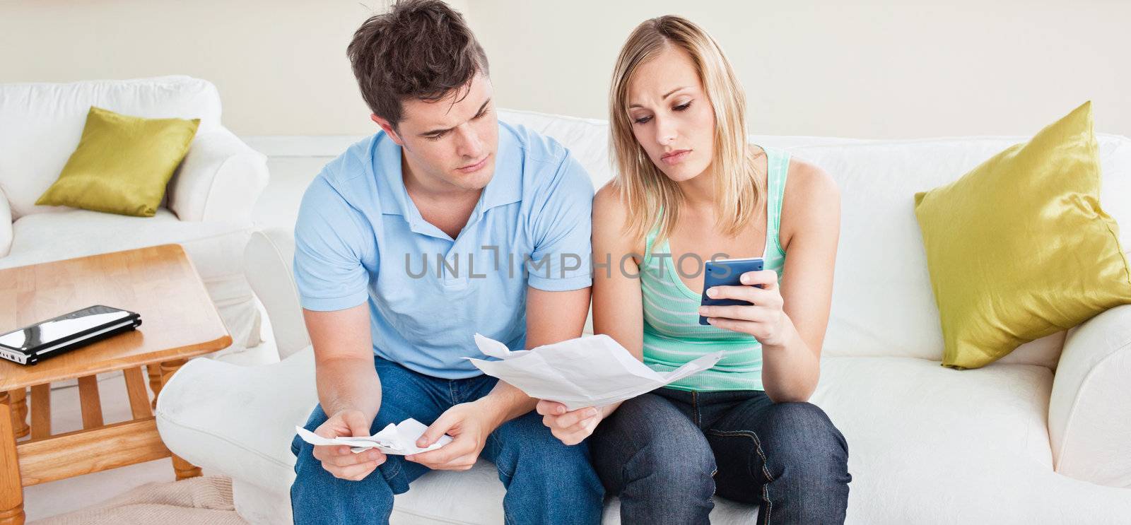 concentrated young couple calculating bills sitting on the sofa in the living-room