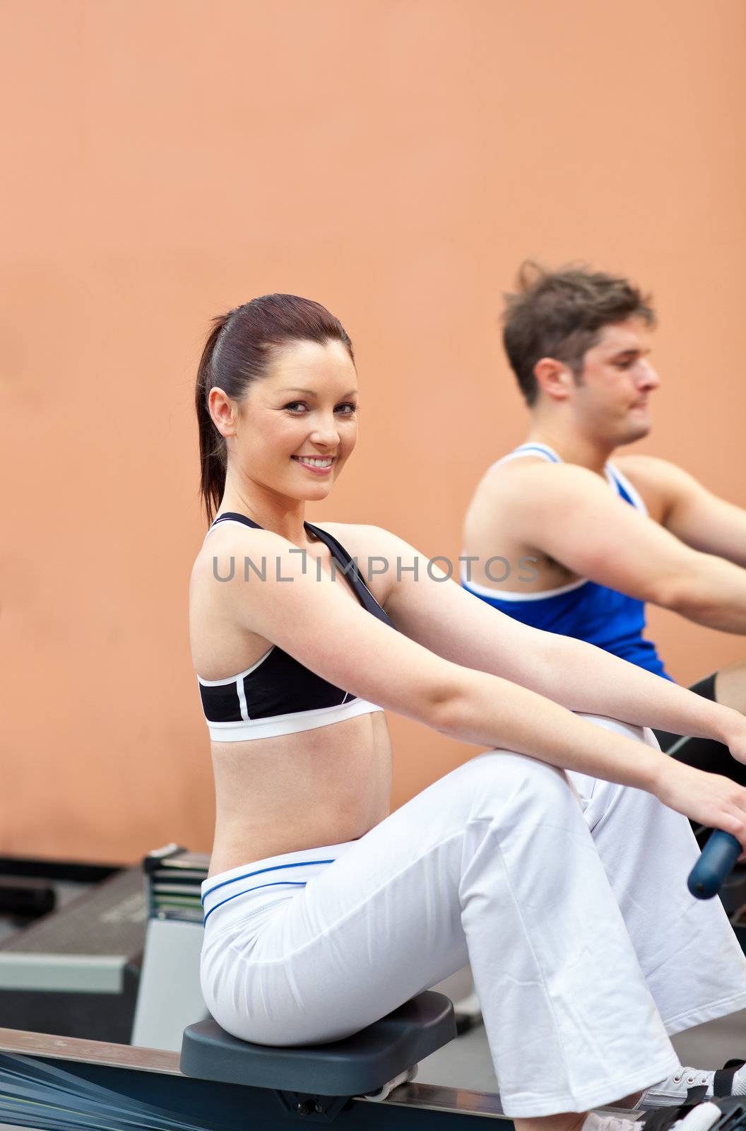 Athletic young people using a rower in a fitness center by Wavebreakmedia