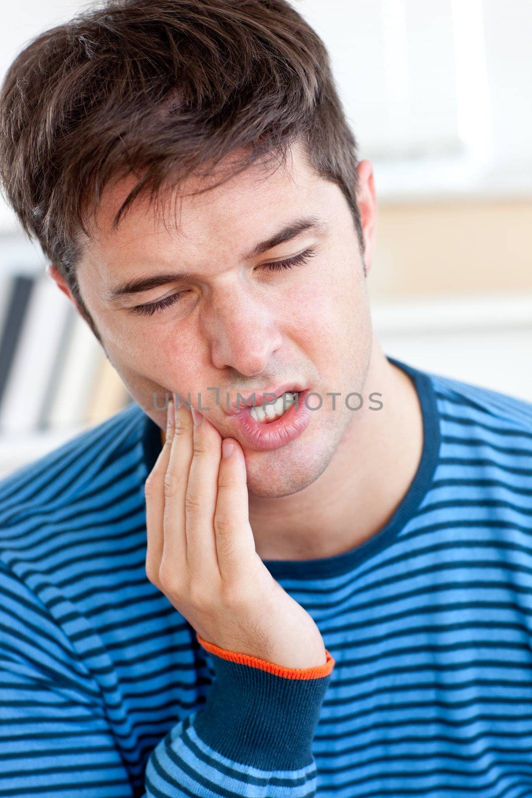 portrait of a man having a raging toothache sitting in the livin by Wavebreakmedia