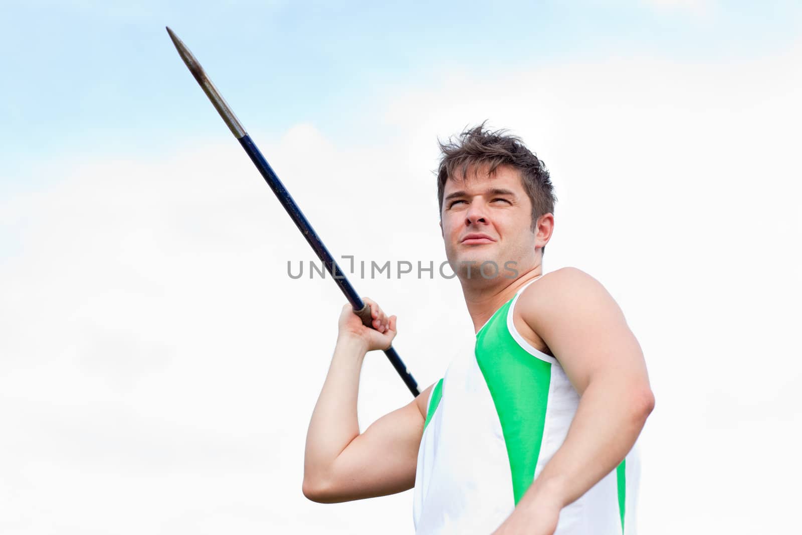 Handsome male throwing a javelin outdoors in a stadium