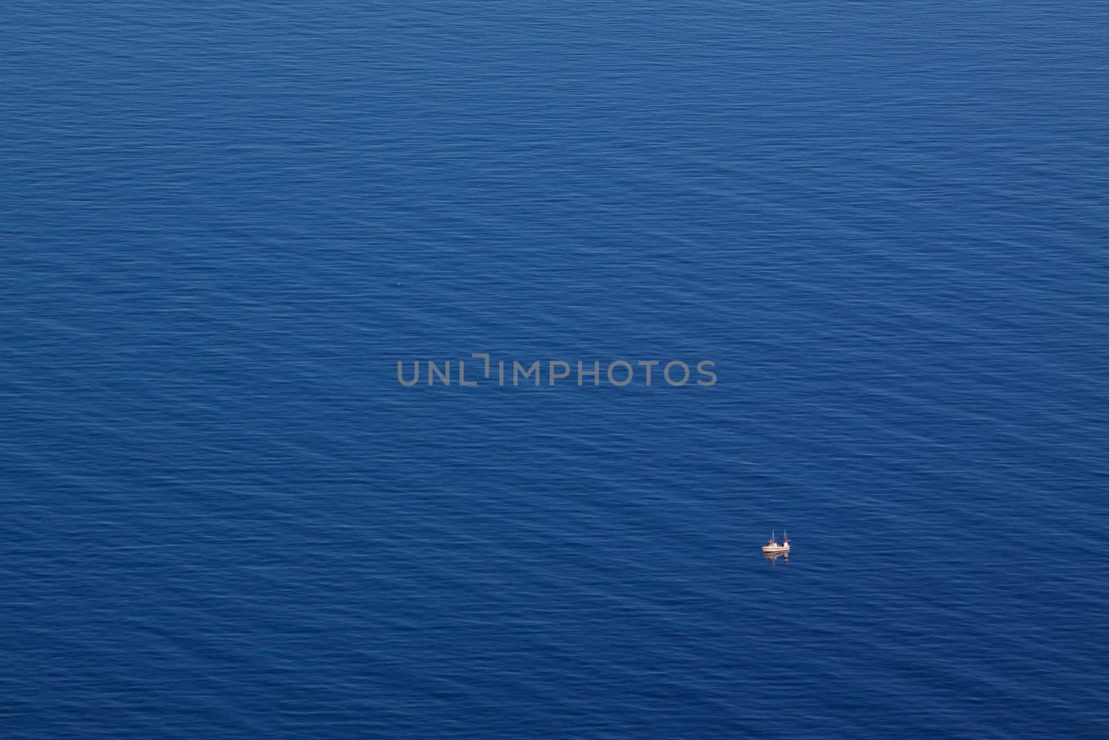Bird's eye view of blue arctic sea with tiny norwegian fishing boat