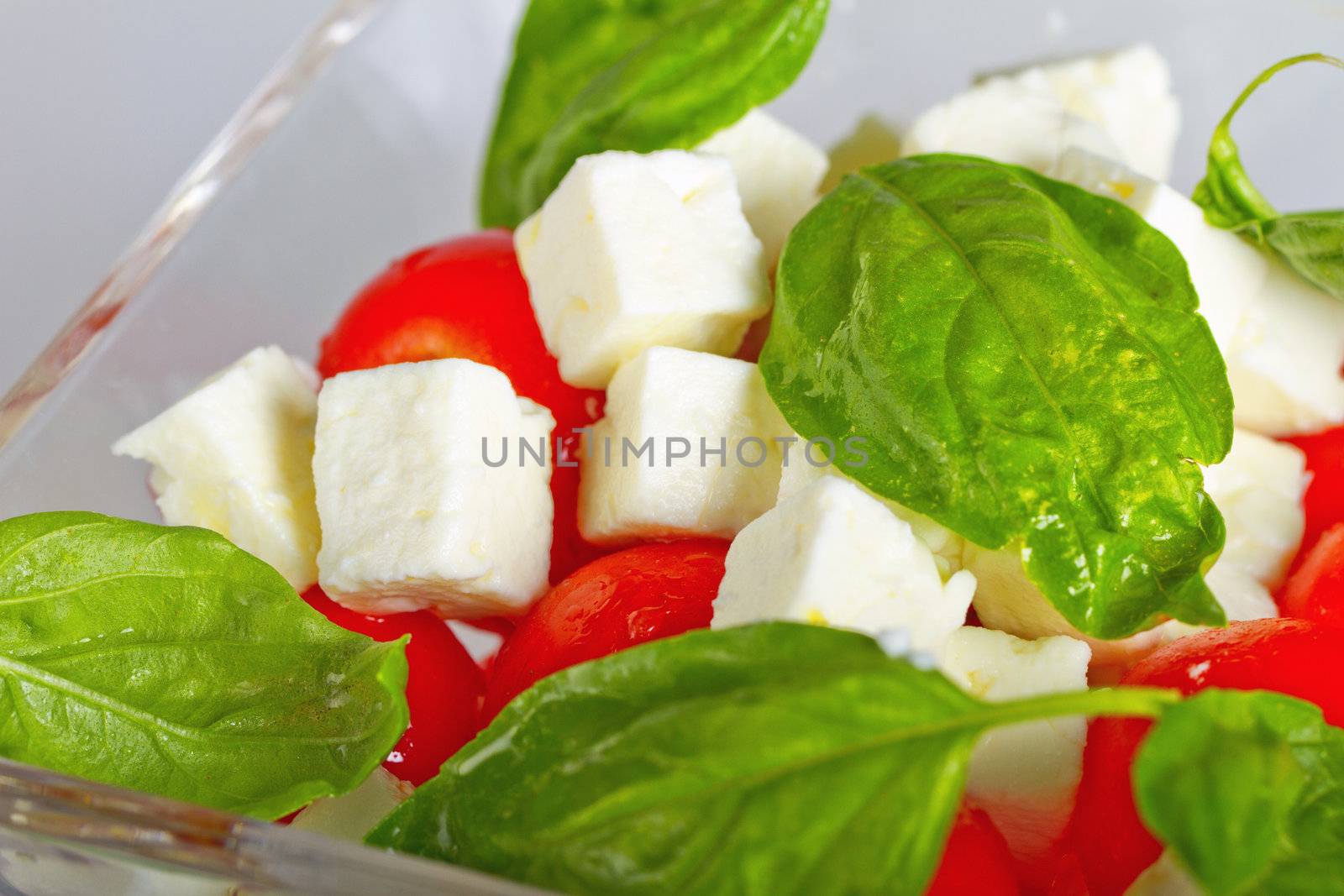 Glass cup of salad with cheese, tomatoes and basil