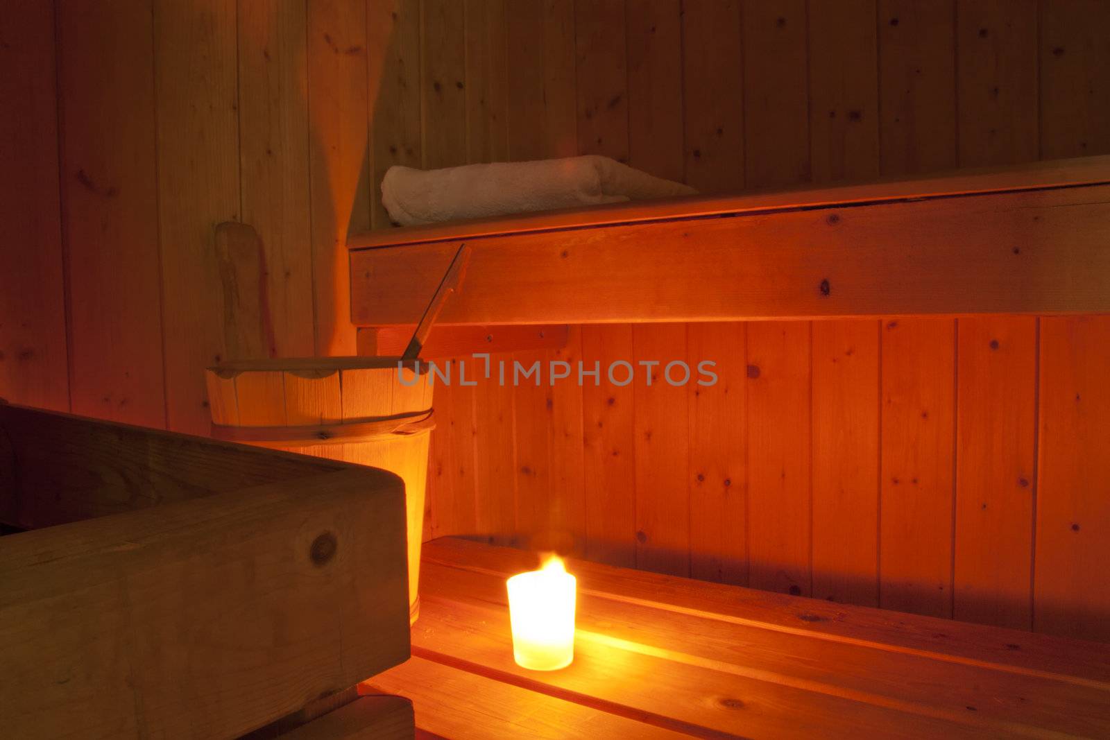 A lit candle inside a wooden finnish sauna