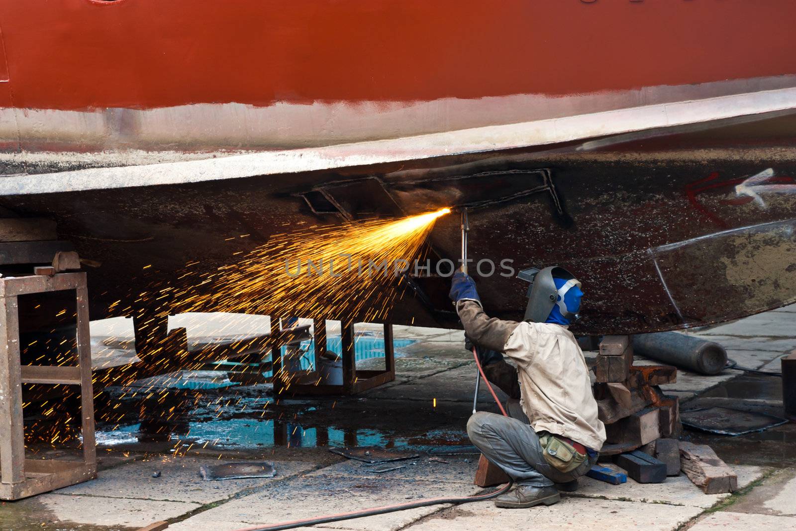 Worker cutting plate ship in dockyard