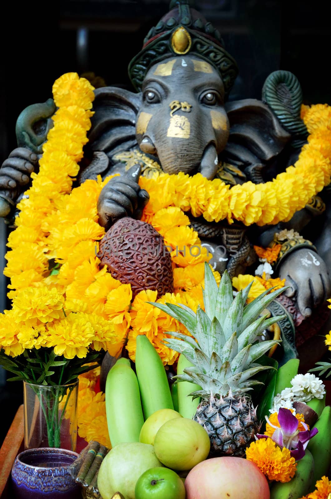 Ganesha figure with fruit and flower offering, Hinduism concept