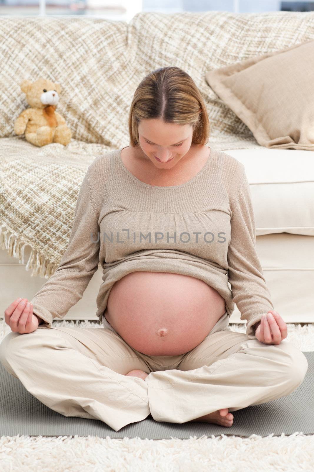 Caucasian pregnant woman doing yoga on the floor in the living-room
