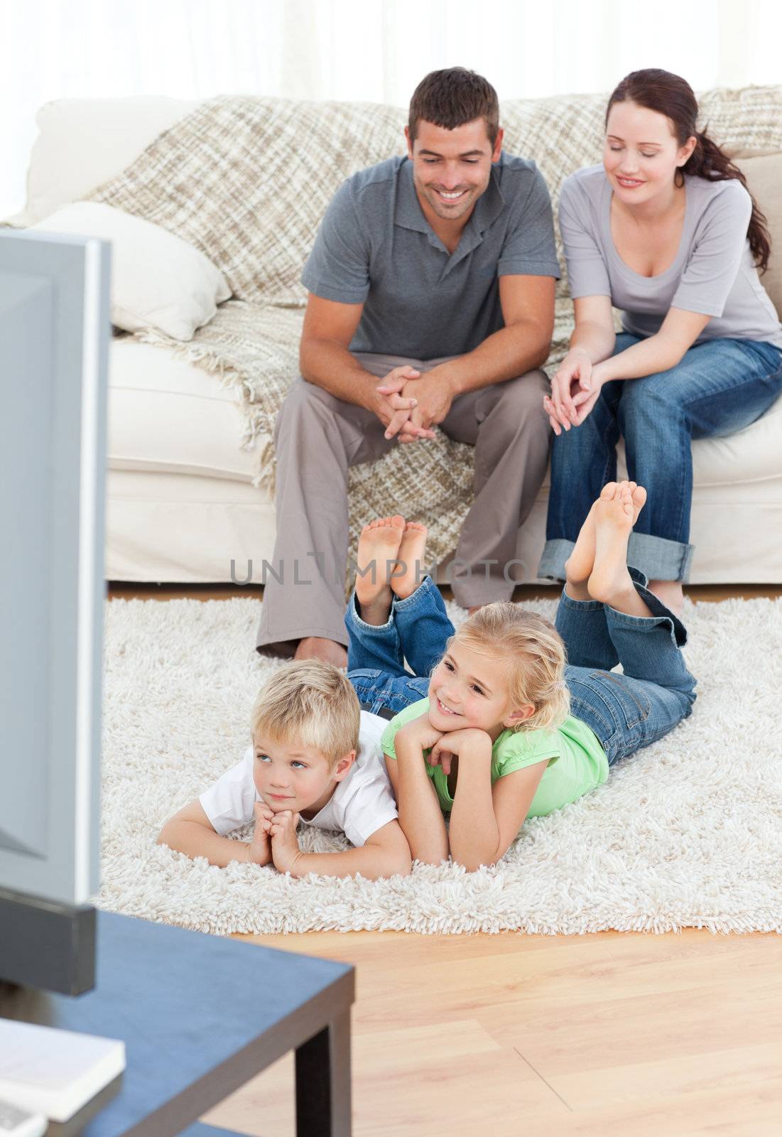 Adorable siblings watching television with their parents lying o by Wavebreakmedia