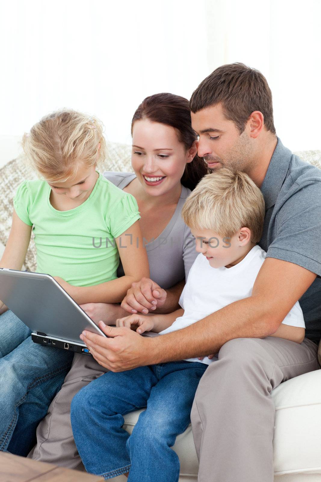 Parents and children using their laptop together sitting on the sofa at home