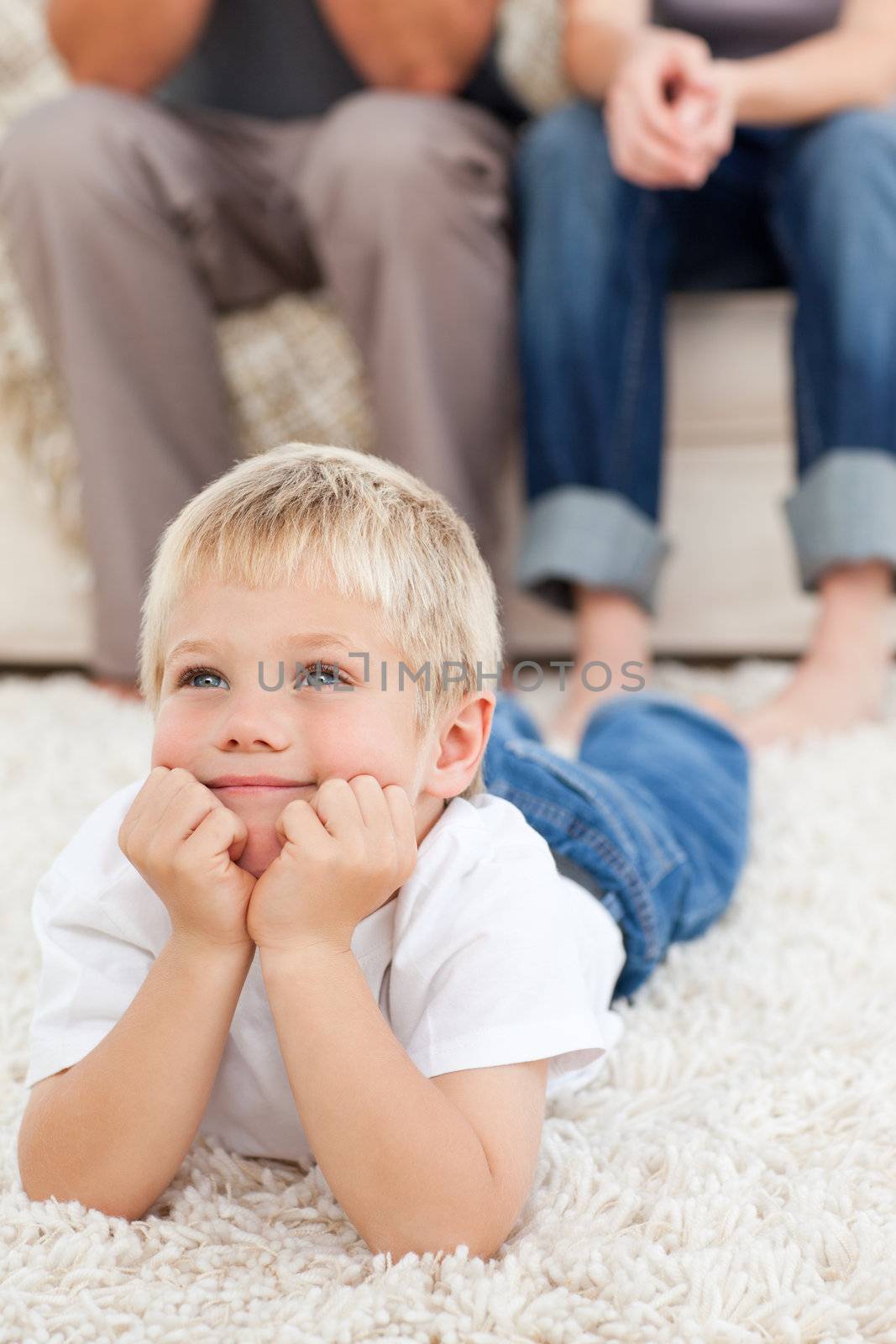 Cute little boy lying on the floor and watching television with  by Wavebreakmedia
