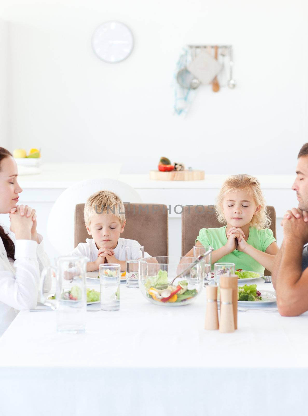 Parents and their children praying during their lunch by Wavebreakmedia