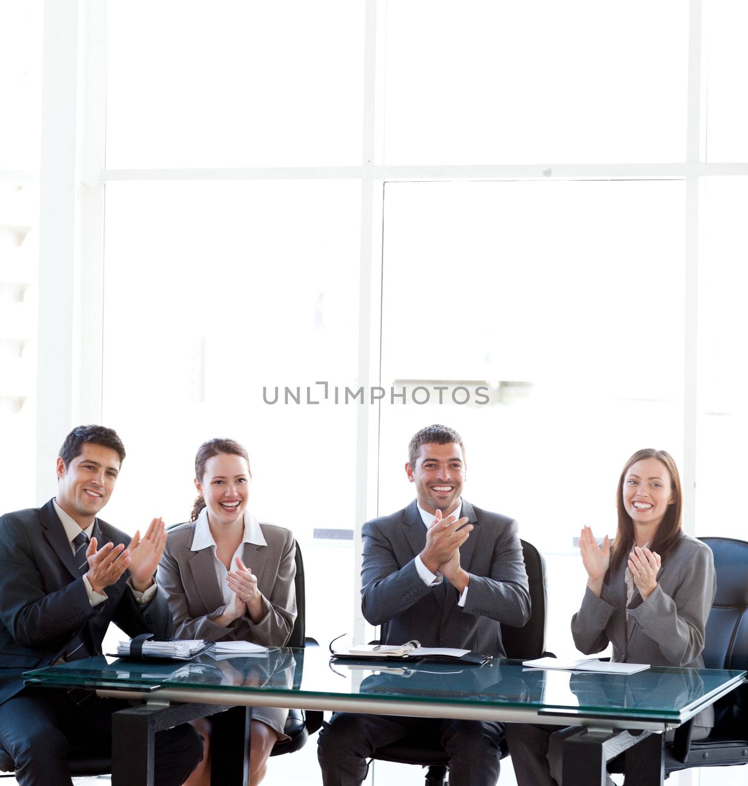 Happy businessteam applauding during a presentation sitting around a table