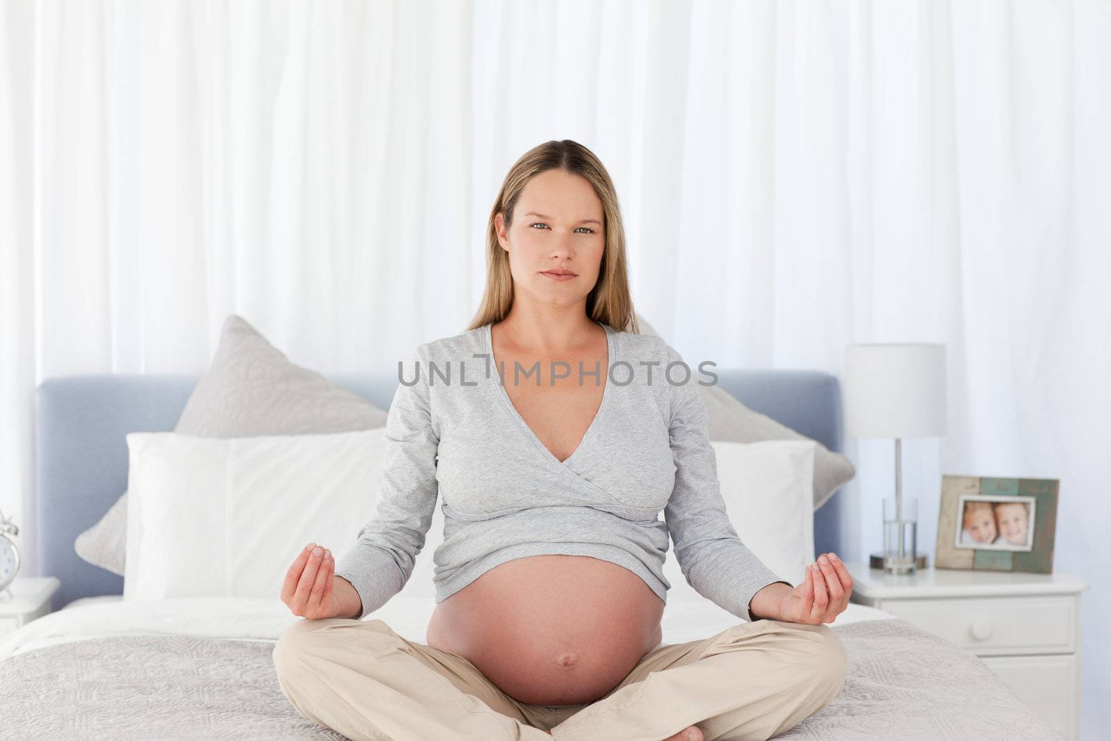 Serious future mom doing meditation on a bed at home