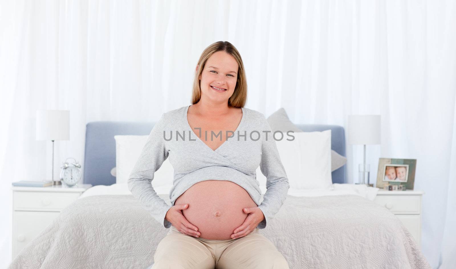 Joyfull pregnant woman in her bedroom smiling at the camera