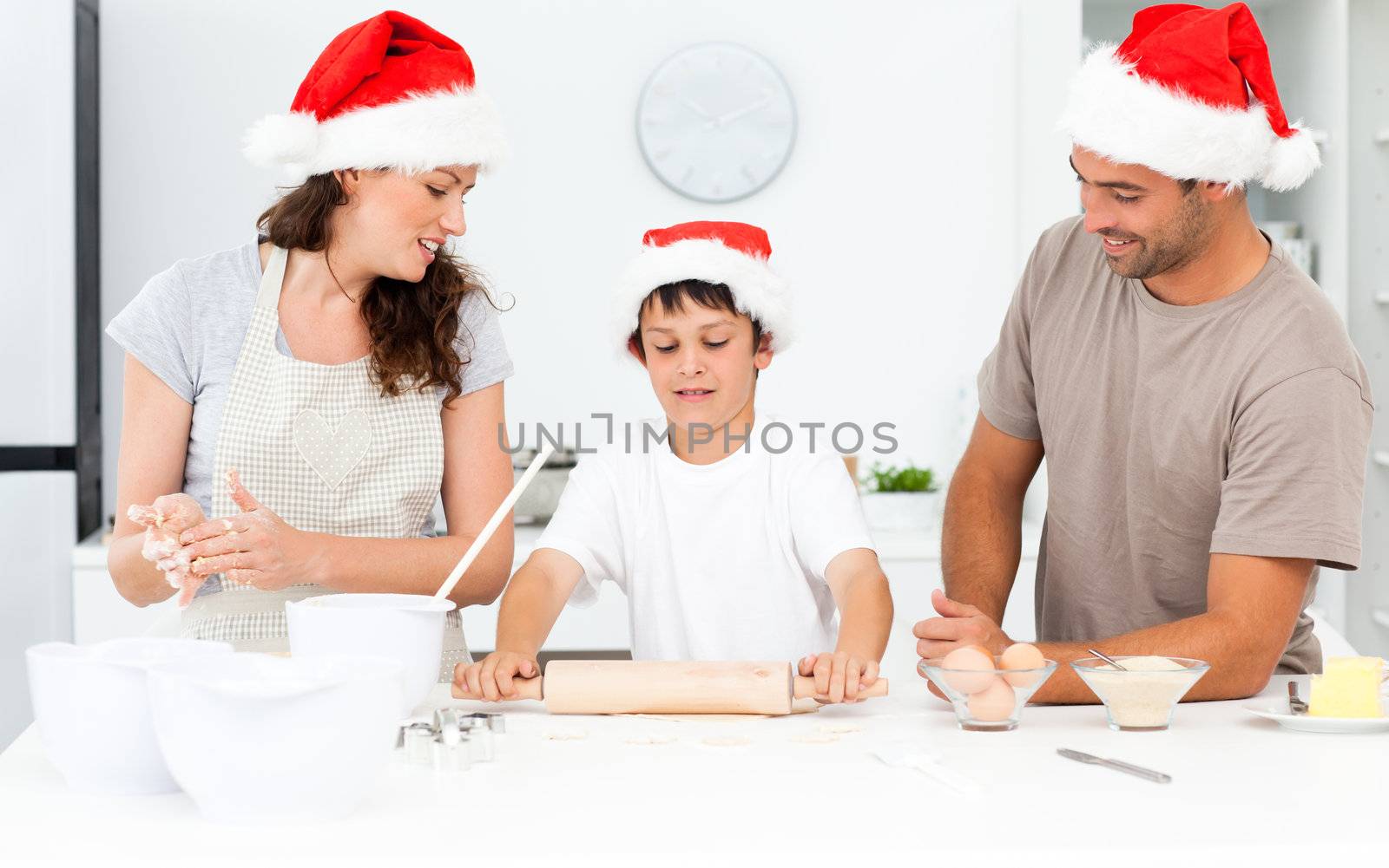 Proud parents looking at their son using a rolling pin by Wavebreakmedia