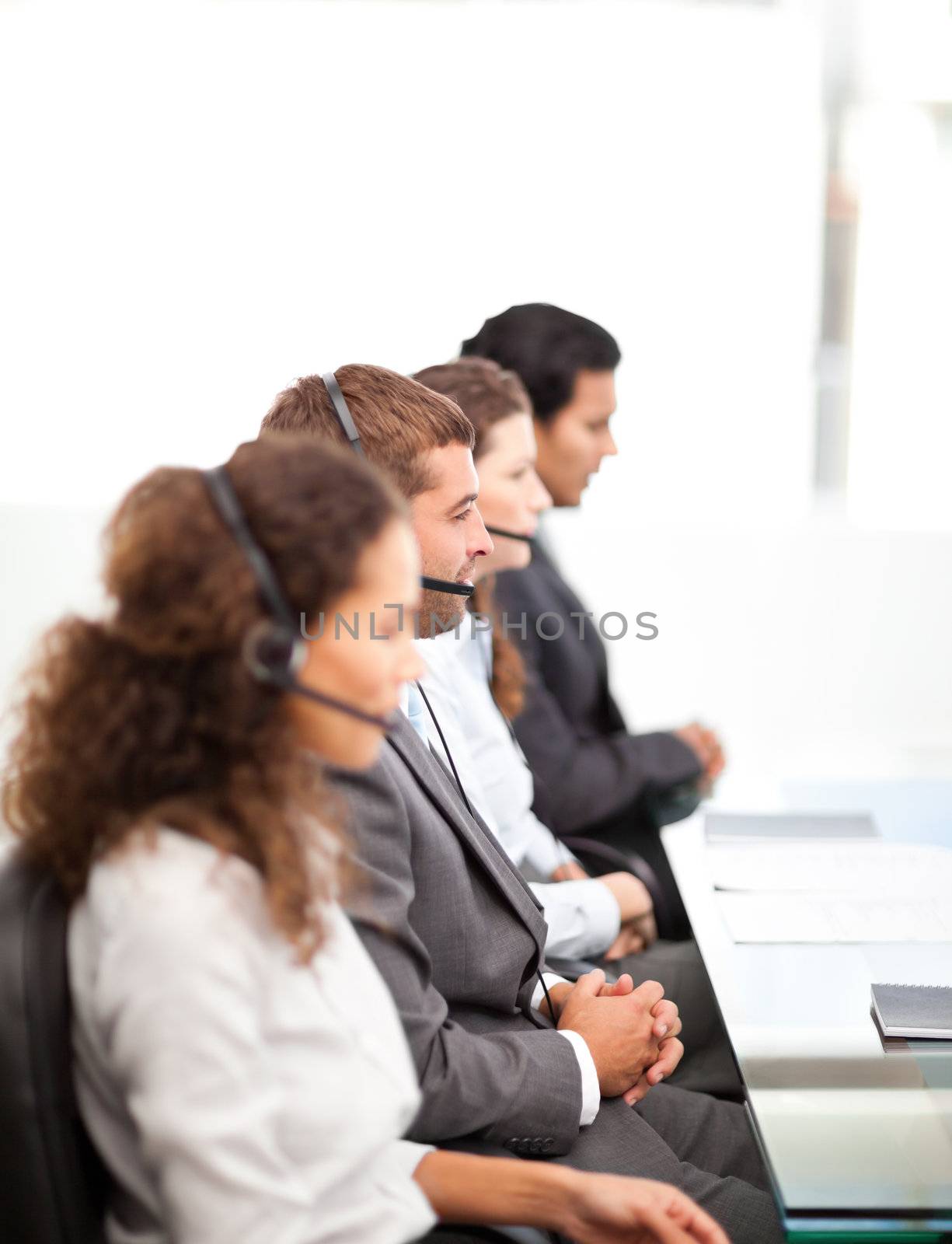 Four businesspeople on the phone sitting at their desk  in a row 