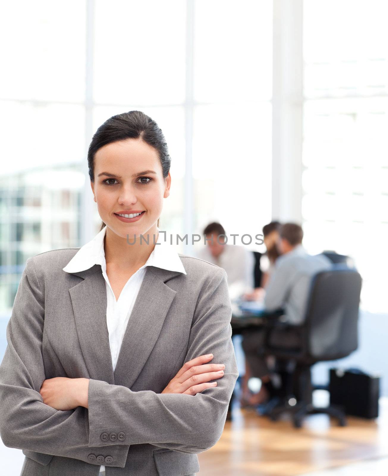 Cheerful businesswoman standing in front of her team while working in the background