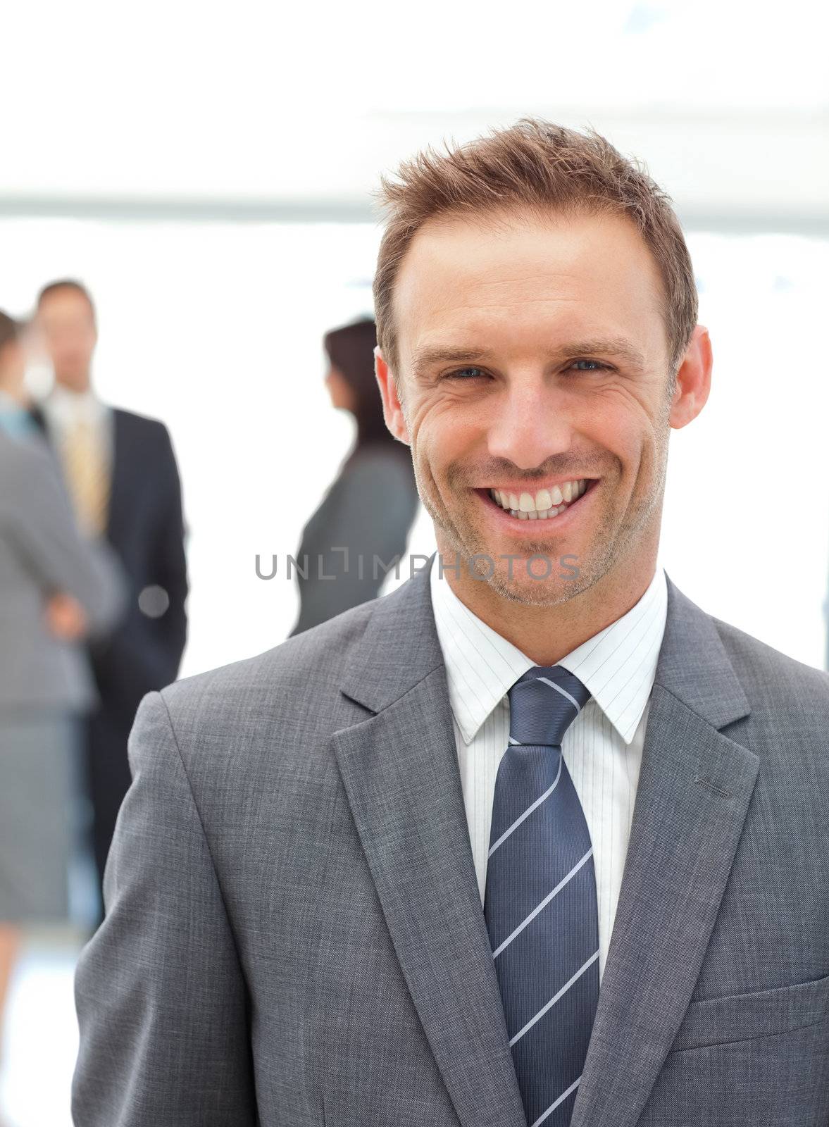 Happy manager standing in front of his team while talking on the background