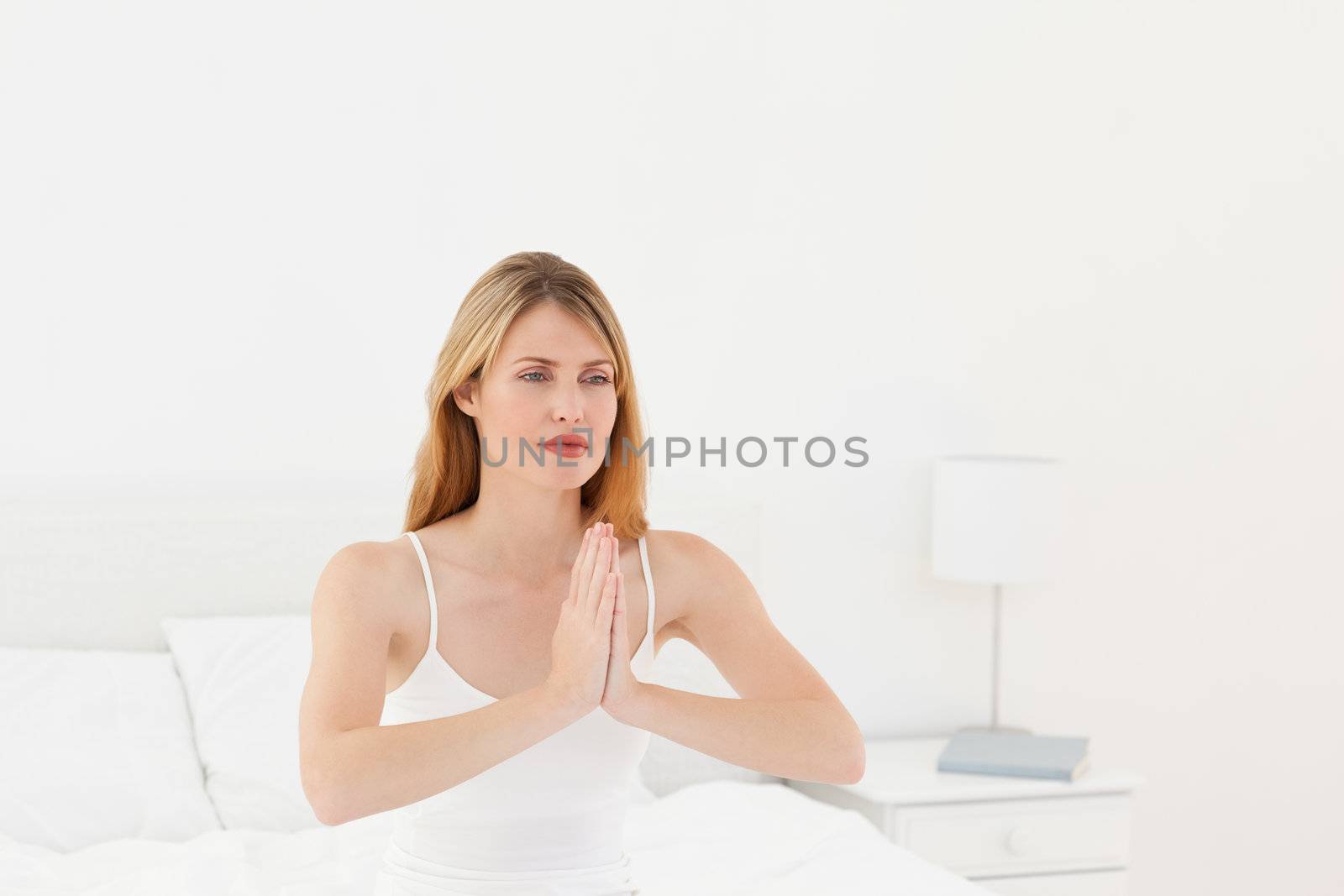 Woman practice yoga on her bed by Wavebreakmedia
