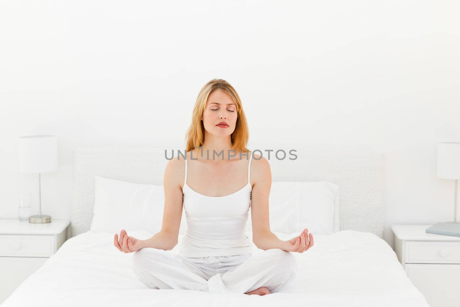 Woman practicing yoga on her bed at home