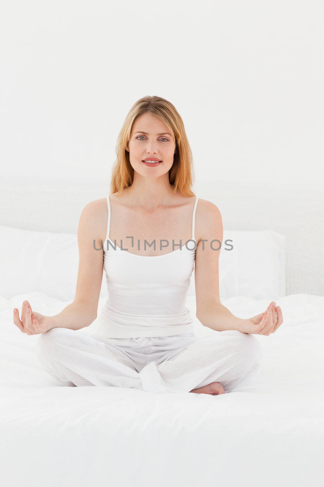 Woman practicing yoga on her bed at home