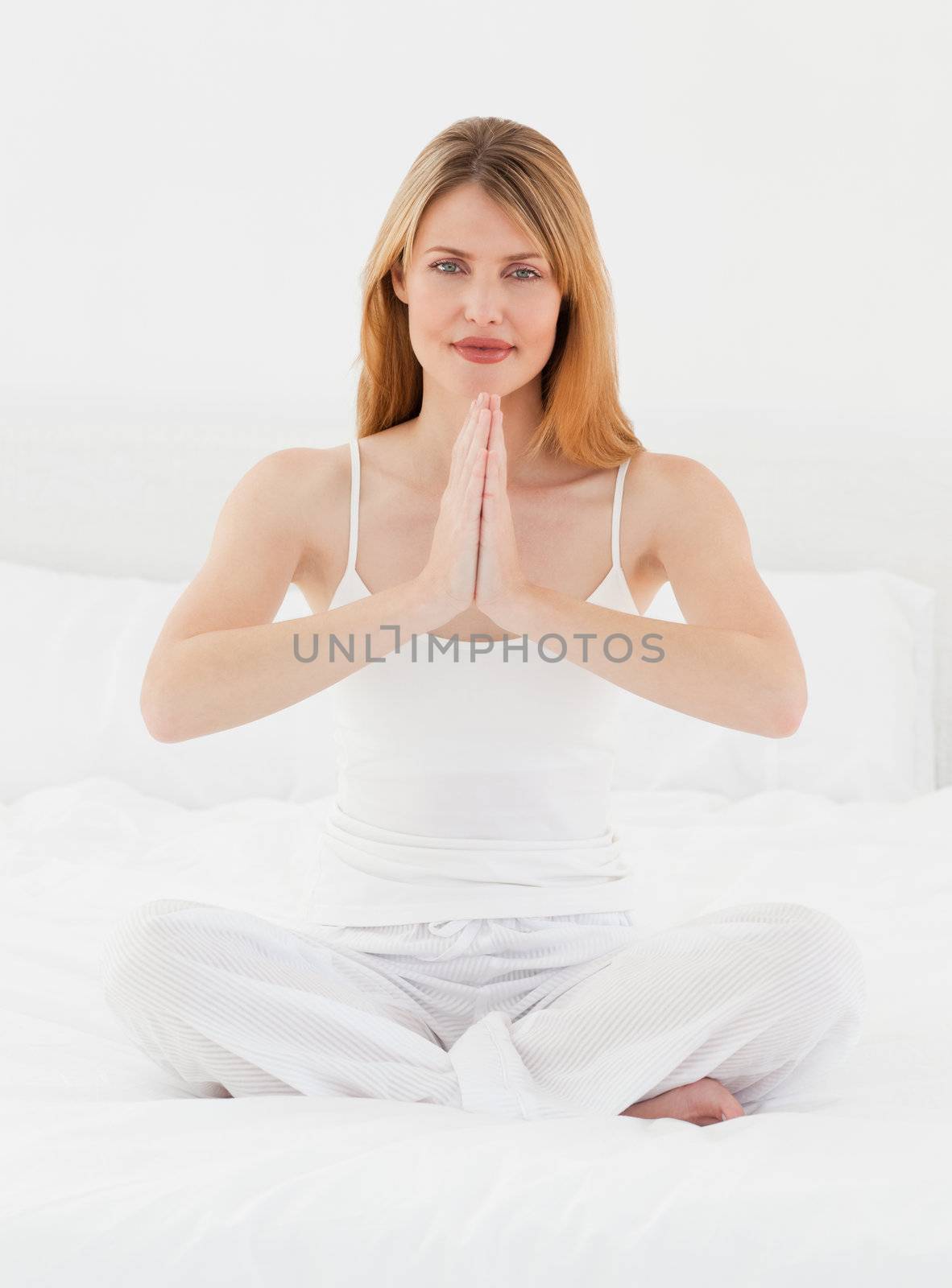 Woman practicing yoga on her bed at home