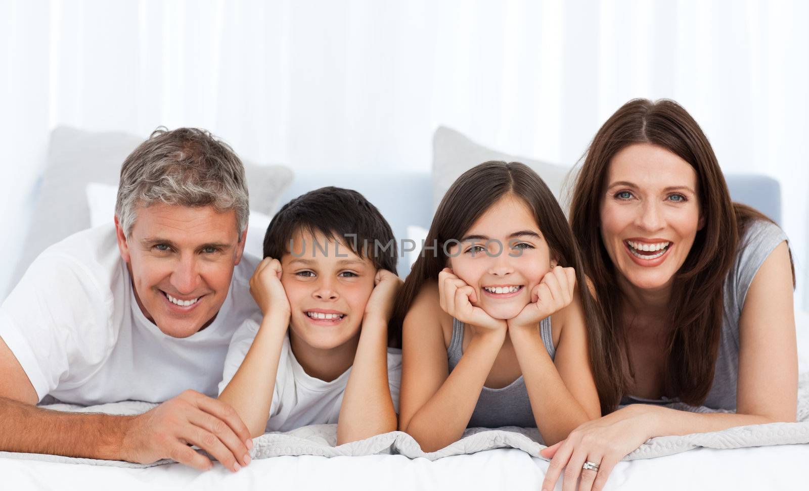 Happy familly looking at the camera on their bed