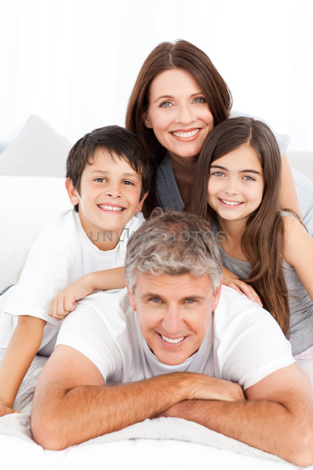 Happy familly looking at the camera on their bed