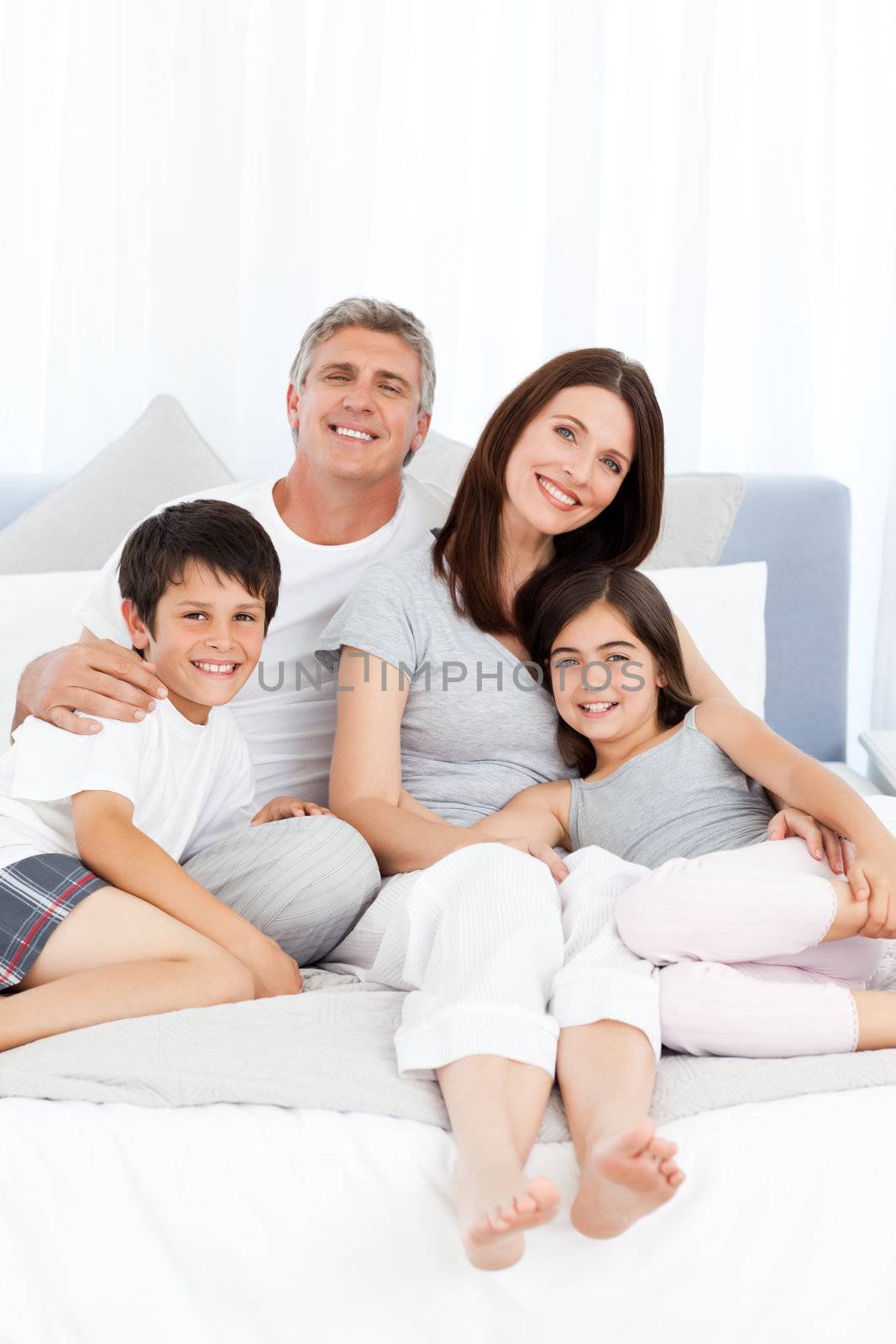 Family lying down on their bed at home