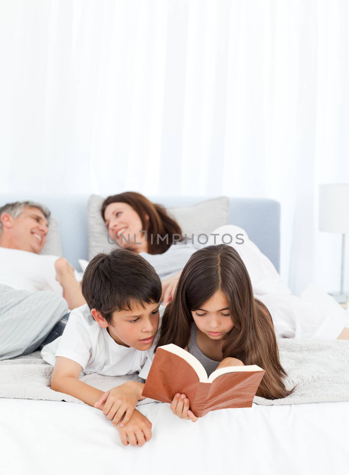 Parents talking while their childrens are reading  on the bed