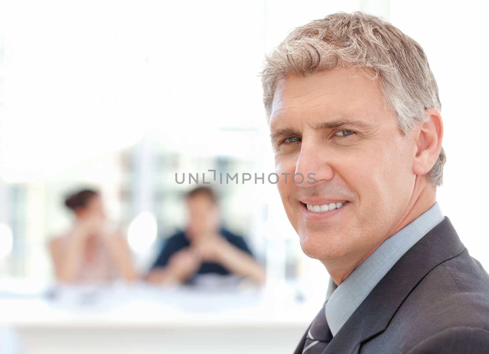 Businessman looking at the camera while the team is working in the background