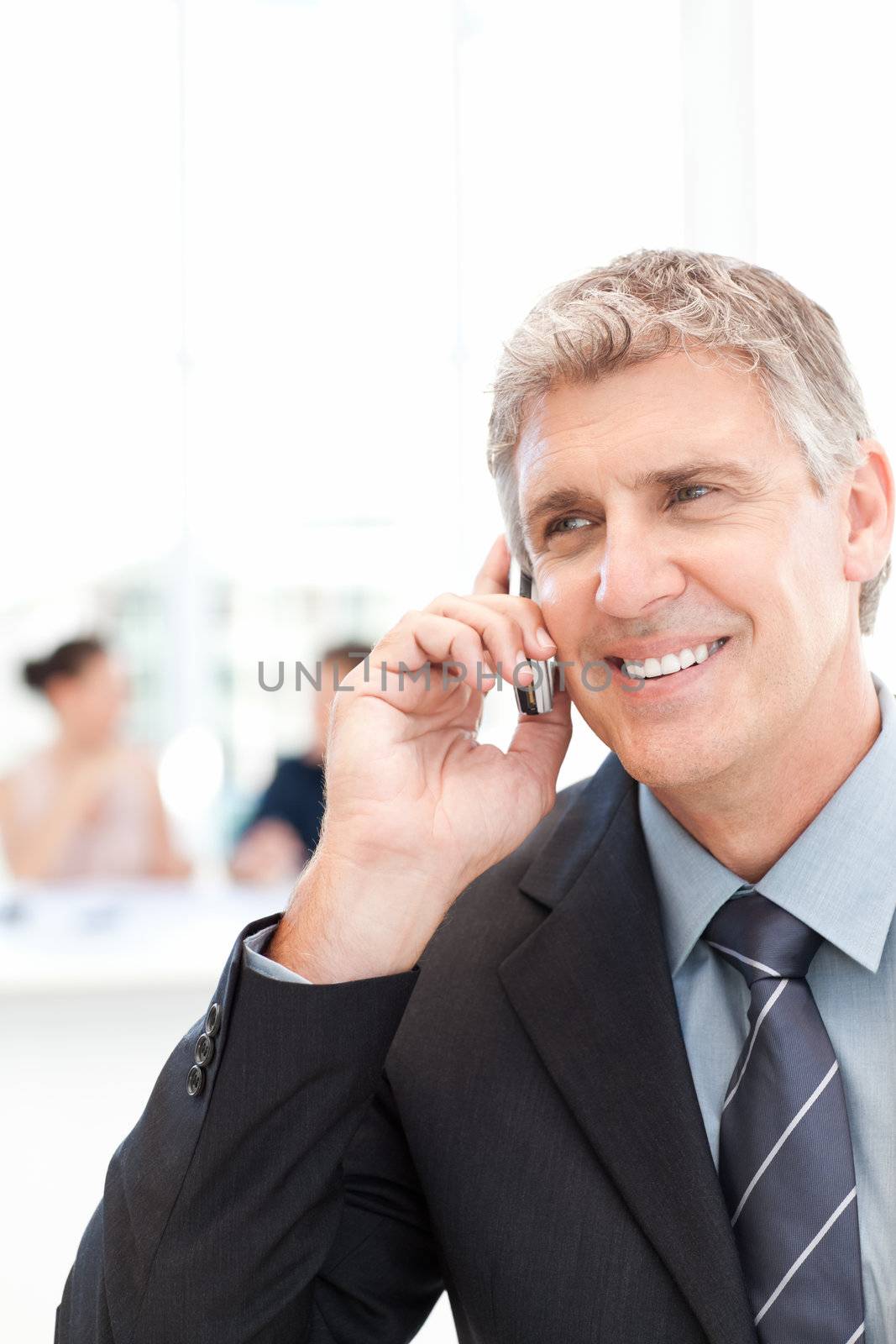 Businessman phoning  while his team is working in the background