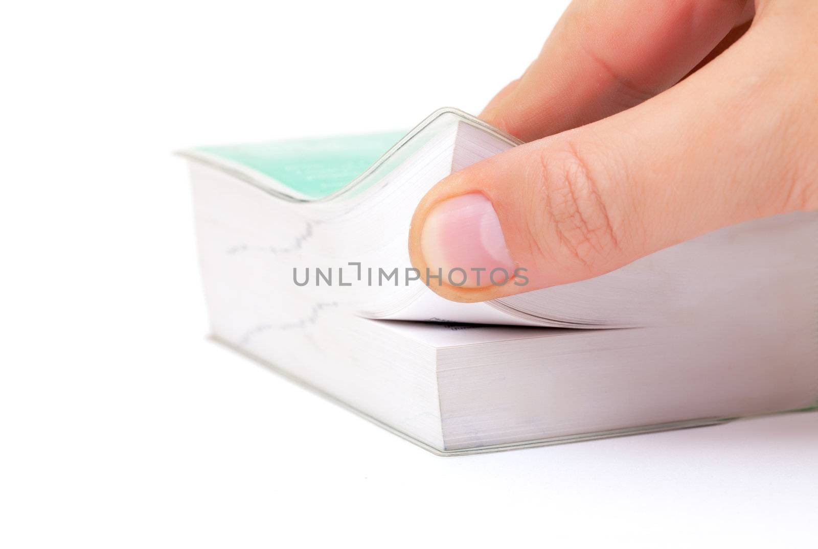 Person thumbing the pages of a book lifting up the corner of a soft cover paperback with their thumb