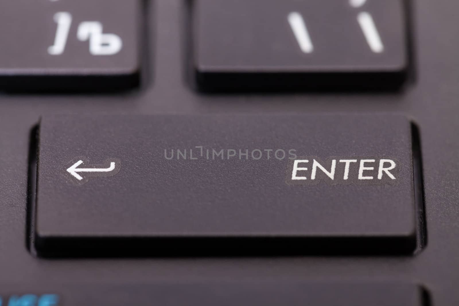 Closeup of an enter key on a computer keyboard or calculator with an arrow on the left