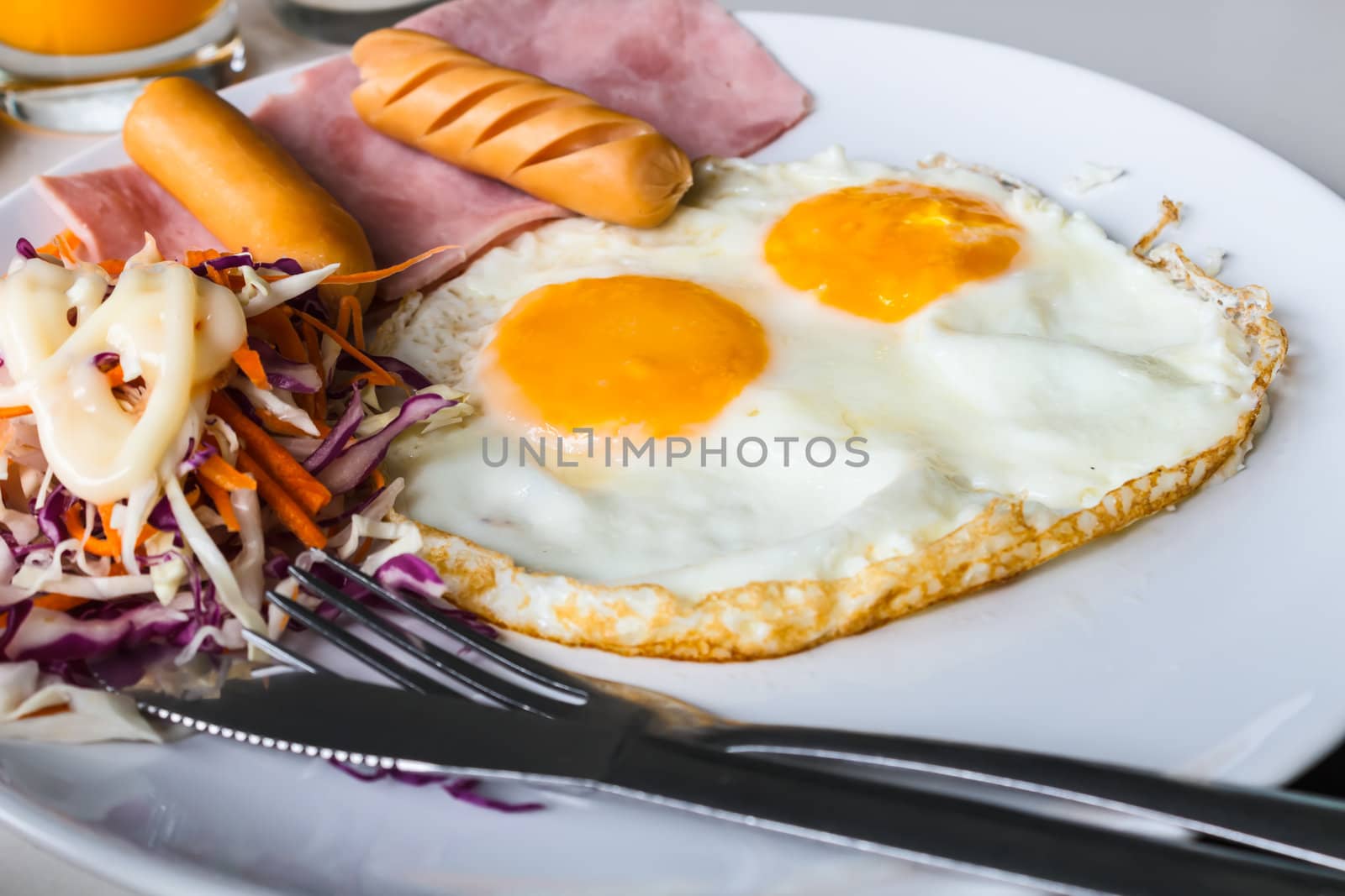 Breakfast with fried eggs, sausages, ham  and salad.