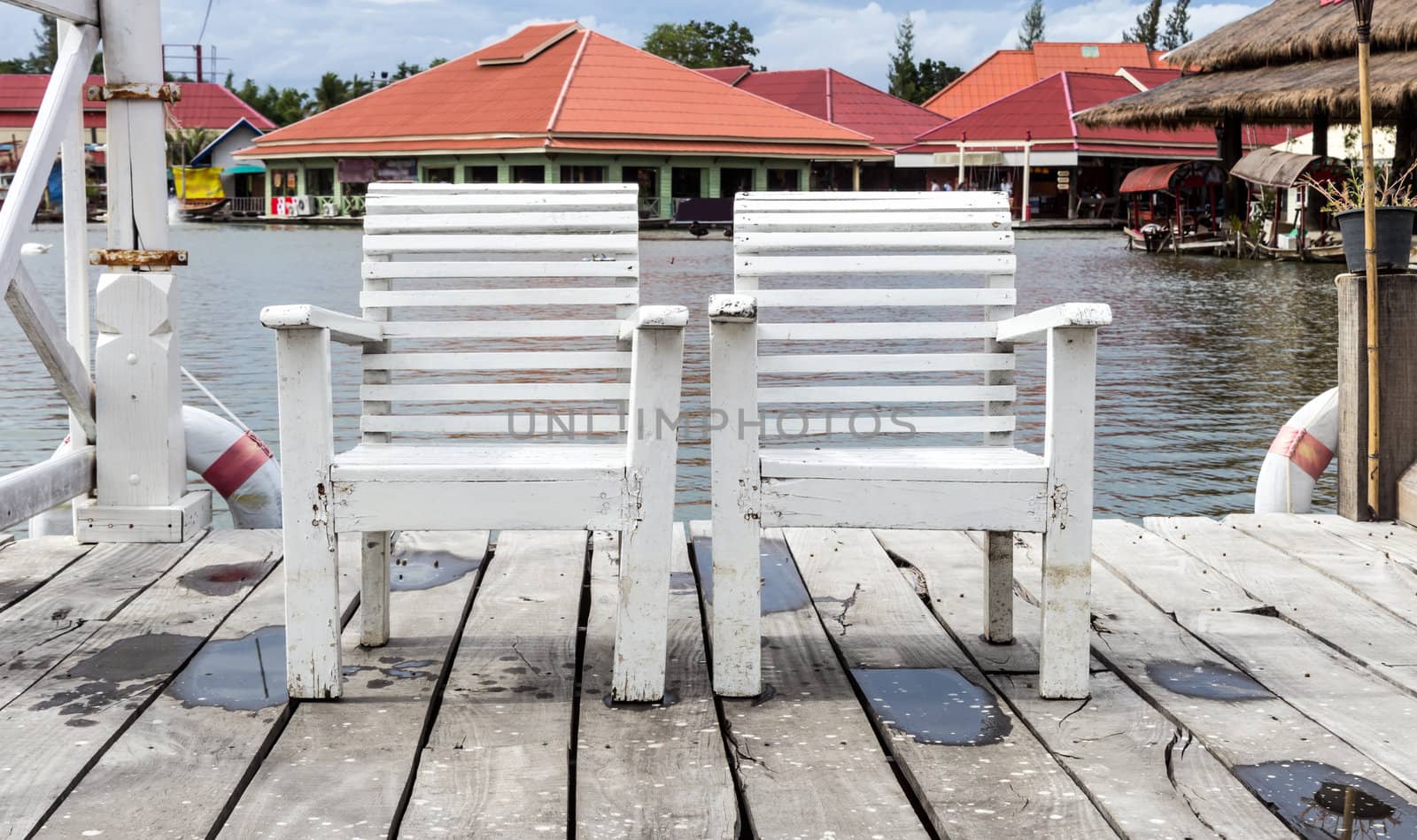 Two white wooden chair beside the lake.
