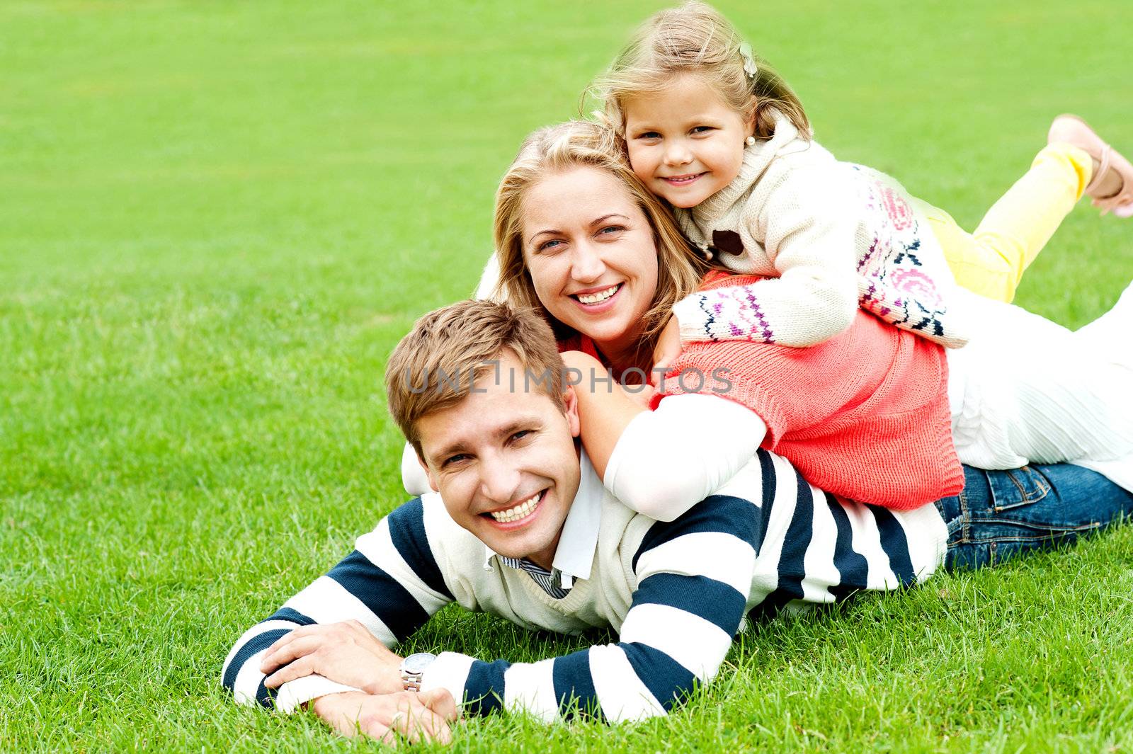 Husband, wife and child piled on each other. Having fun outdoors