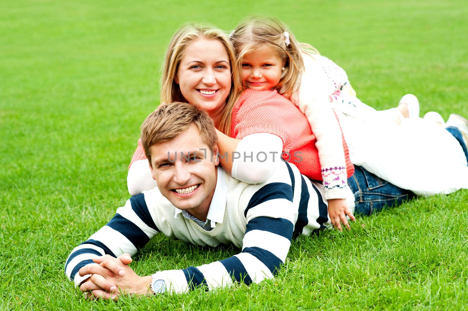Young mother sandwiched between her daughter and husband. Photogenic family of three